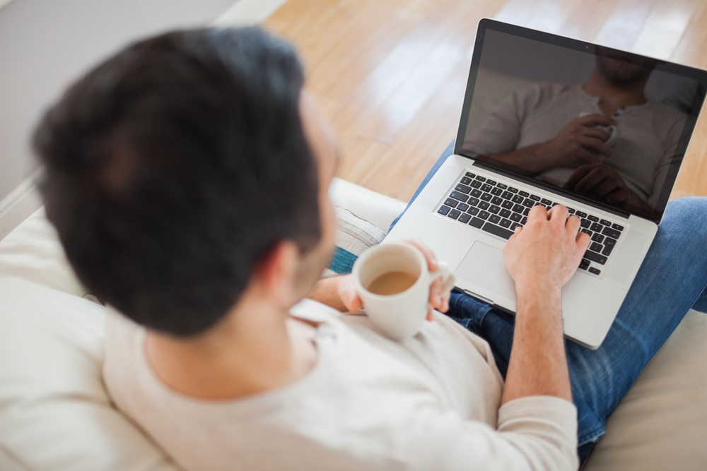 Young man using his laptop in bright living room